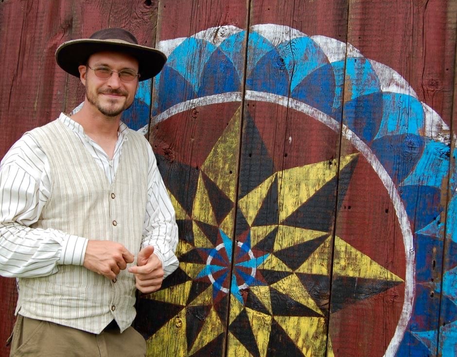 a person standing next to folk art posing for photo