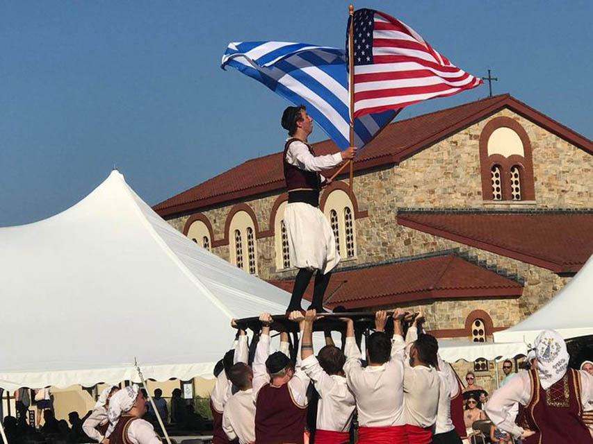 people waving Greek and American flag