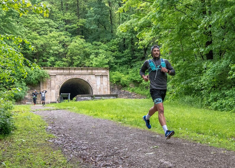 a person running on trail and a tunnel far behind