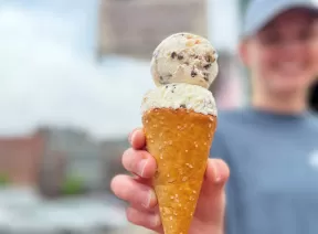 holding a waffle cone with two scoops of ice cream