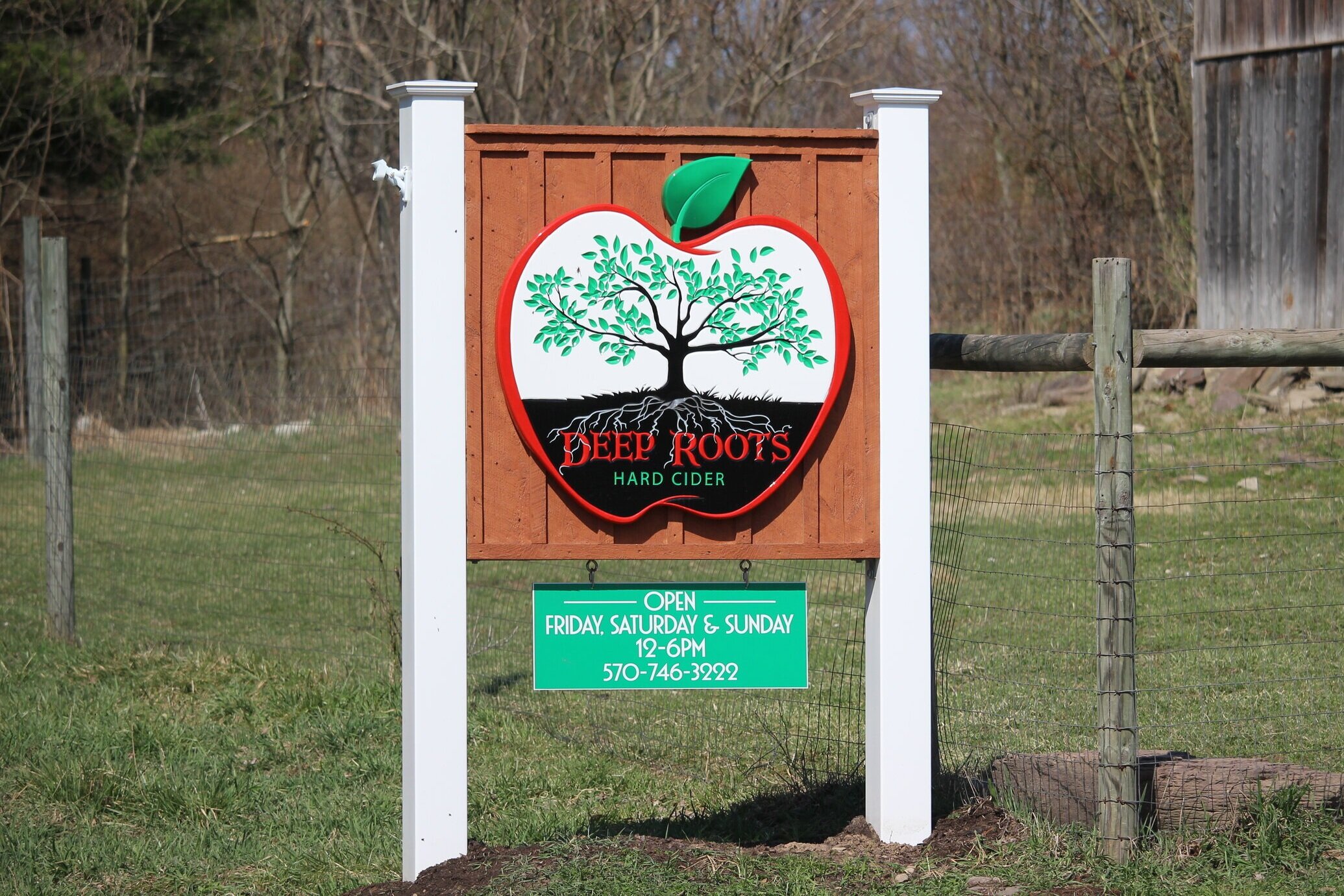 Outdoor sign with apple on it with name of Deep Roots Hard Cider