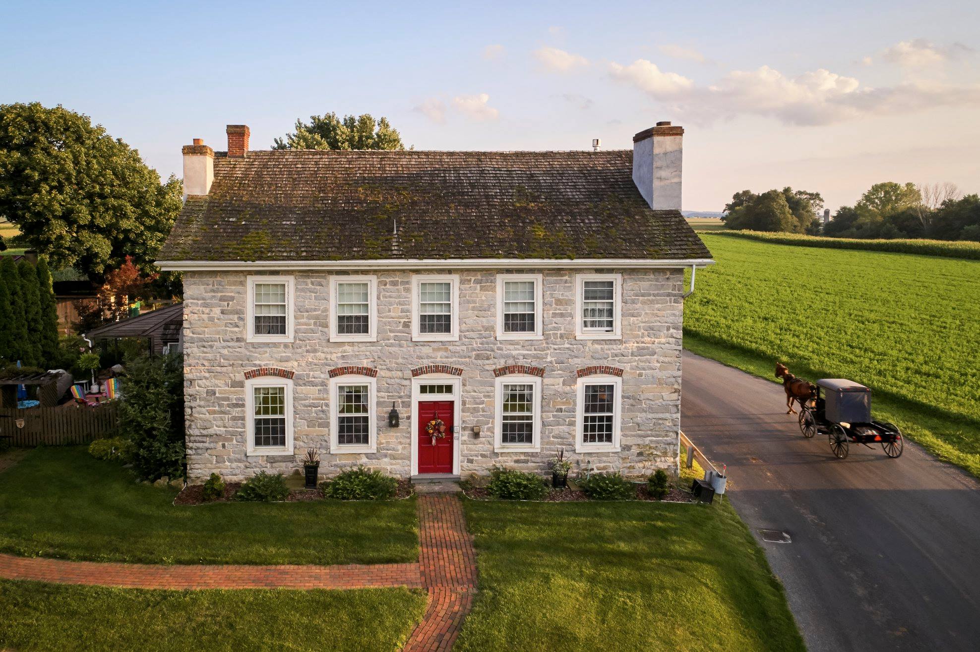 Two story stone bed and breakfast next to a road with an Amish buggy