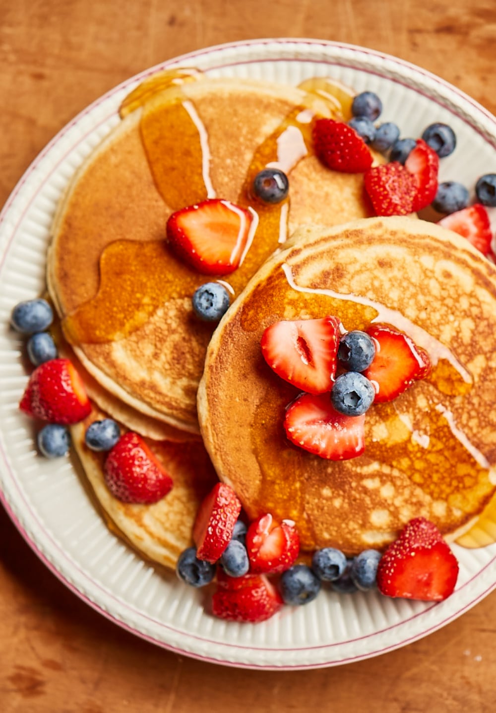 a stack of pancakes with syrup and berries