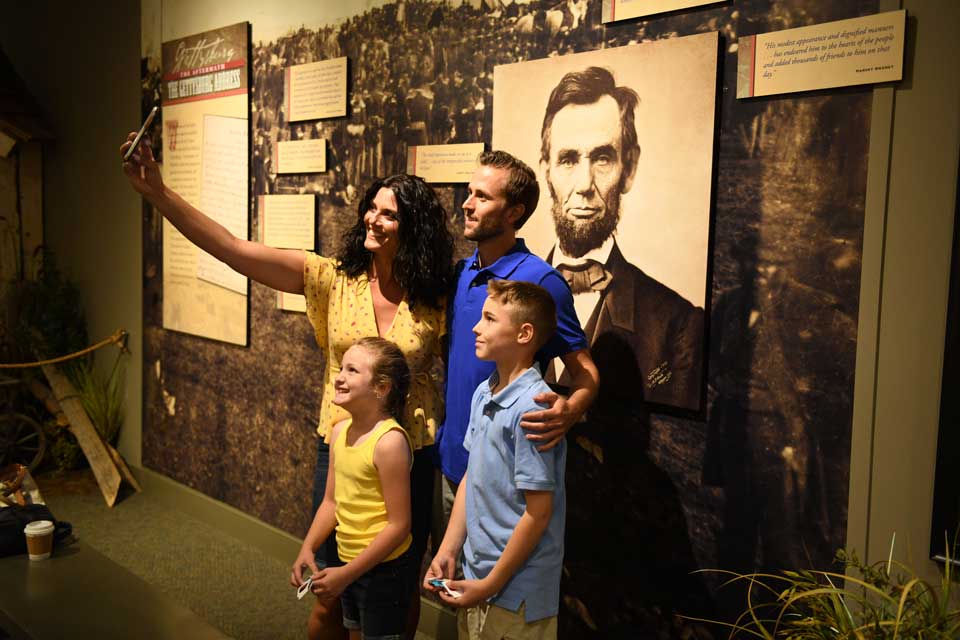 Family taking photo infront of Lincoln Poster