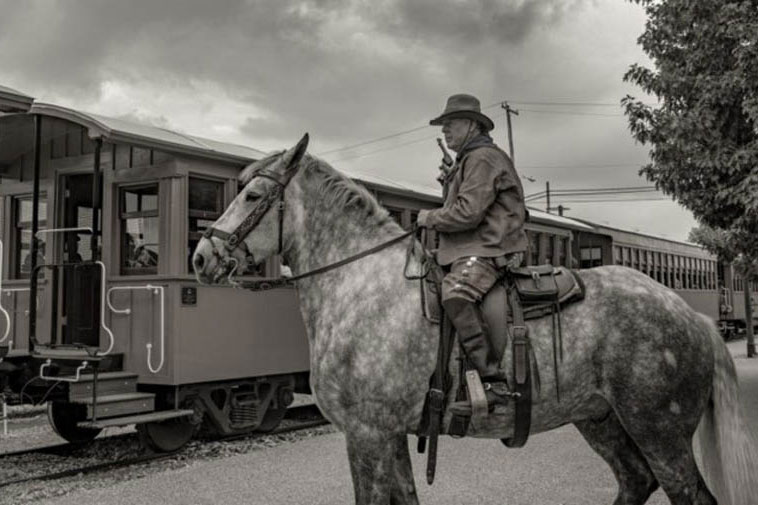 a cowboy on horse at a train yard