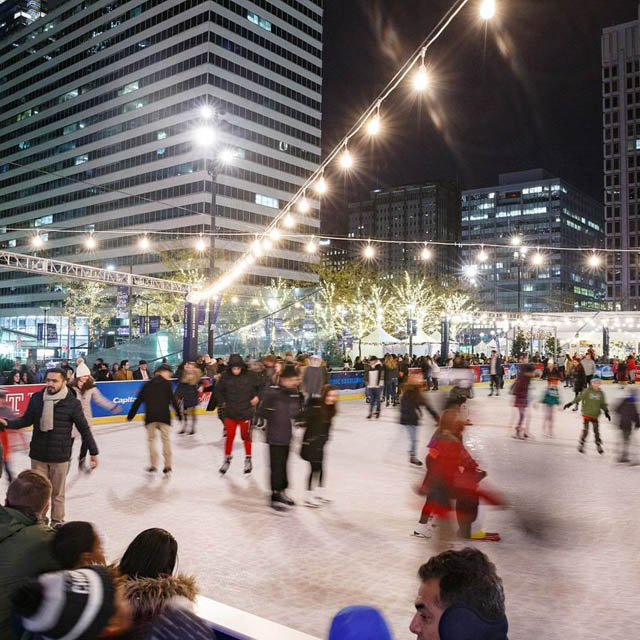 people ice skating on the rink under holiday lights
