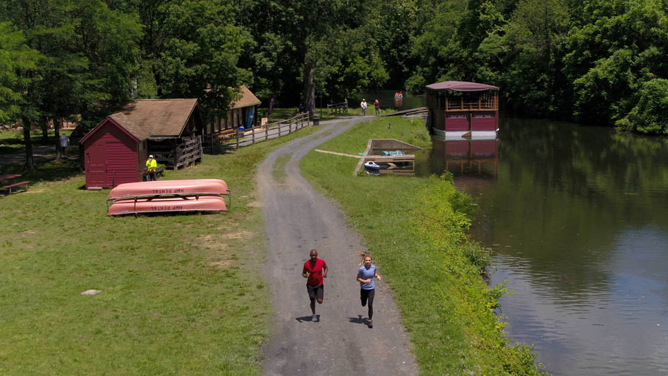 two people running on a trail by water shed