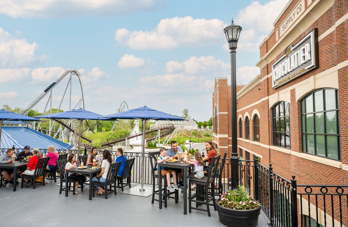 people enjoying food sitting outside with an amusement park view