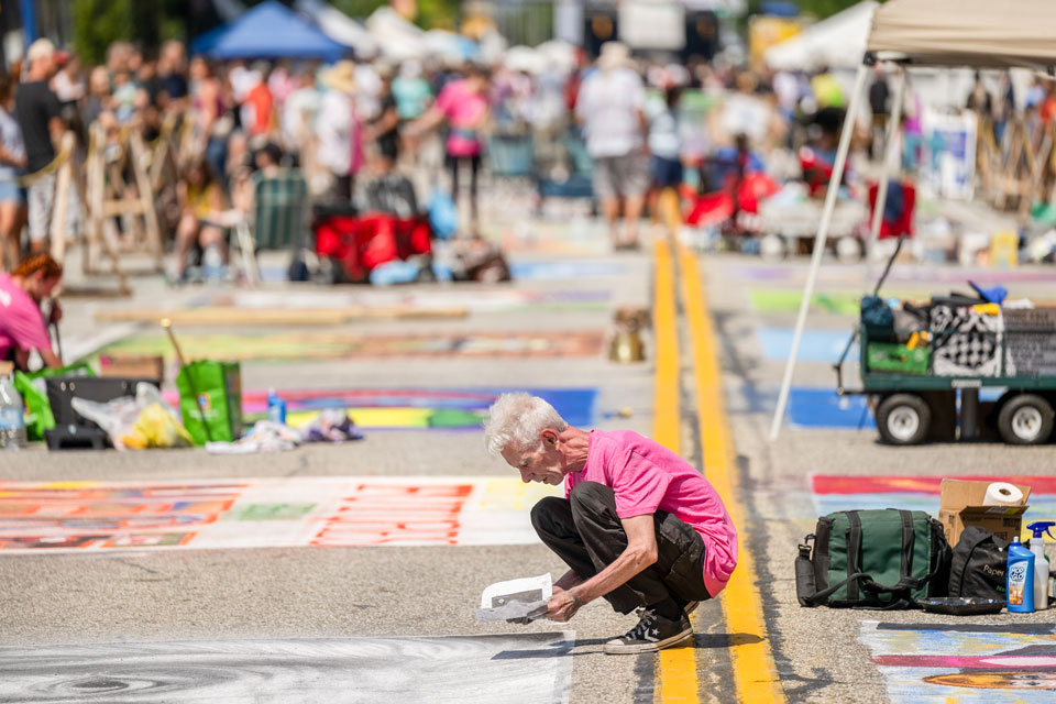 a person doing Chalk walk art on road