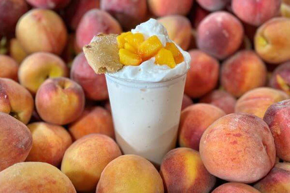 smoothie glass with peaches on top placed in the middle