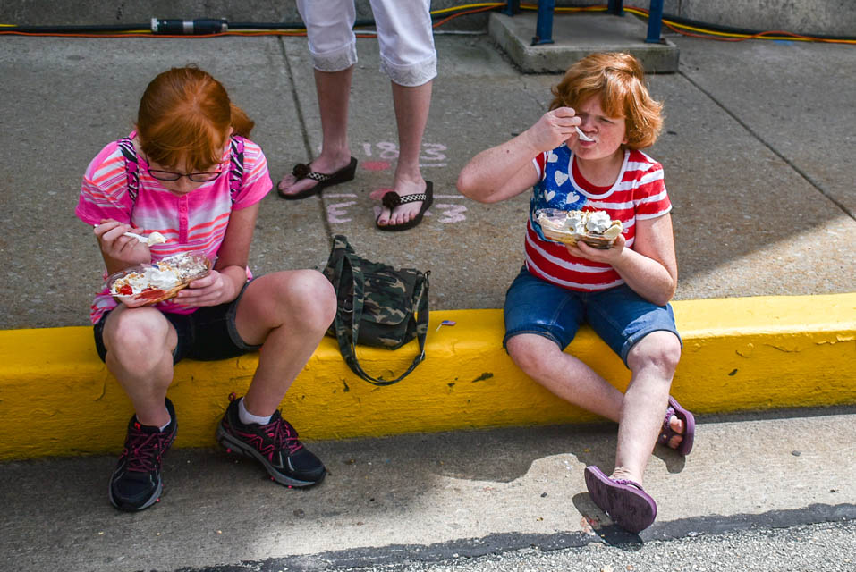 Two kids sitting on curb eating ice cream