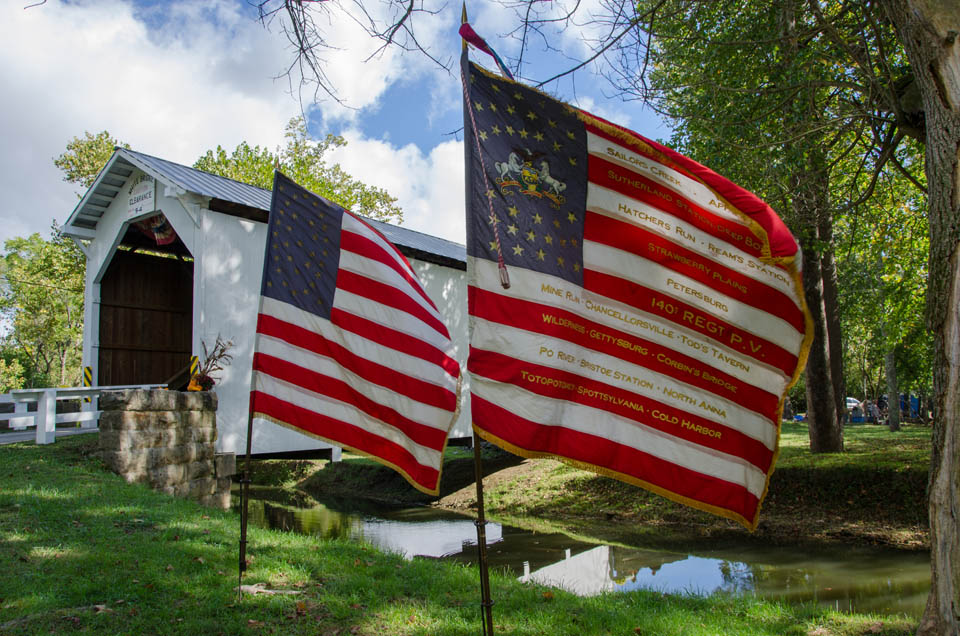 two American flags posted near covered bridge