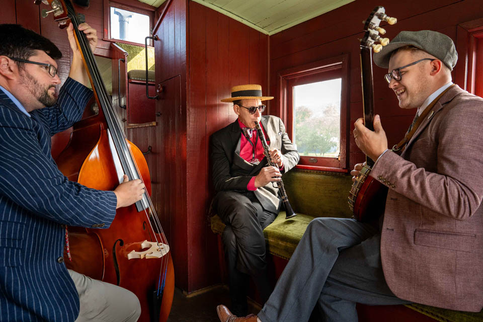 three musicians playing inside a rail wagon
