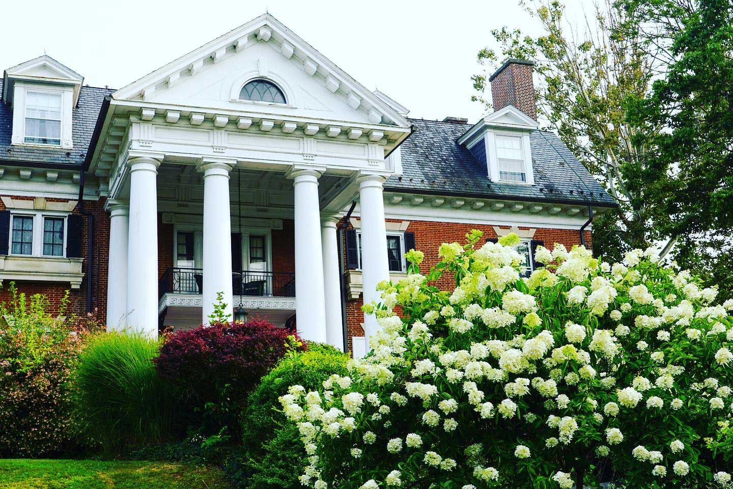 A house with pillars and bushes in front of it