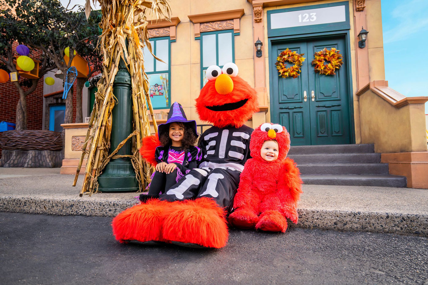 two kids with Halloween costume sitting with sesame street character