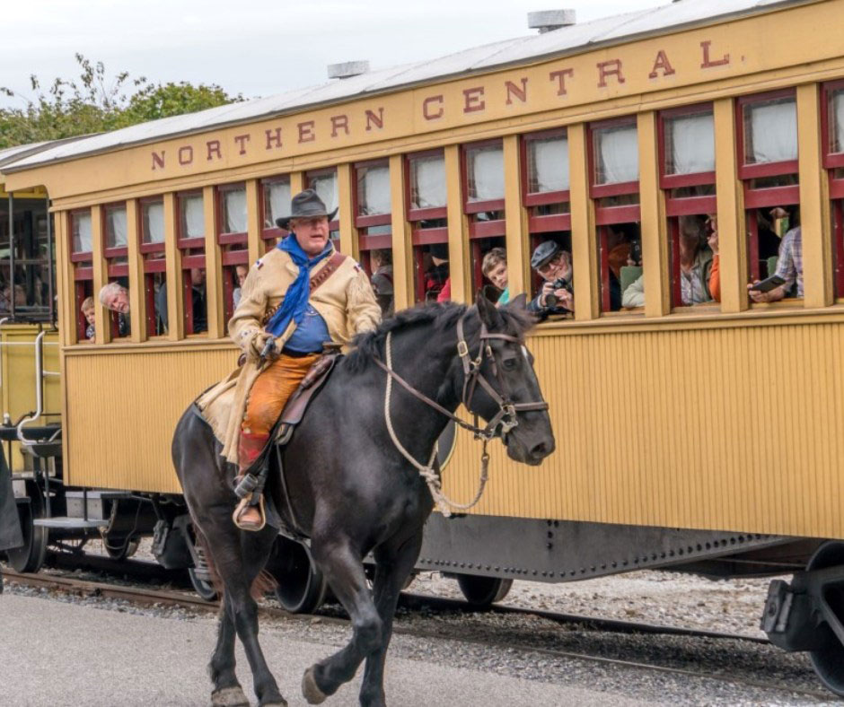 cowboy on horse riding next to train car