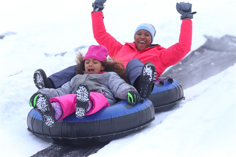 little girl and mother enjoying snowtubing
