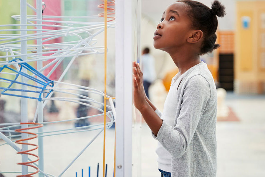 little girl looking at ball run maze artifact
