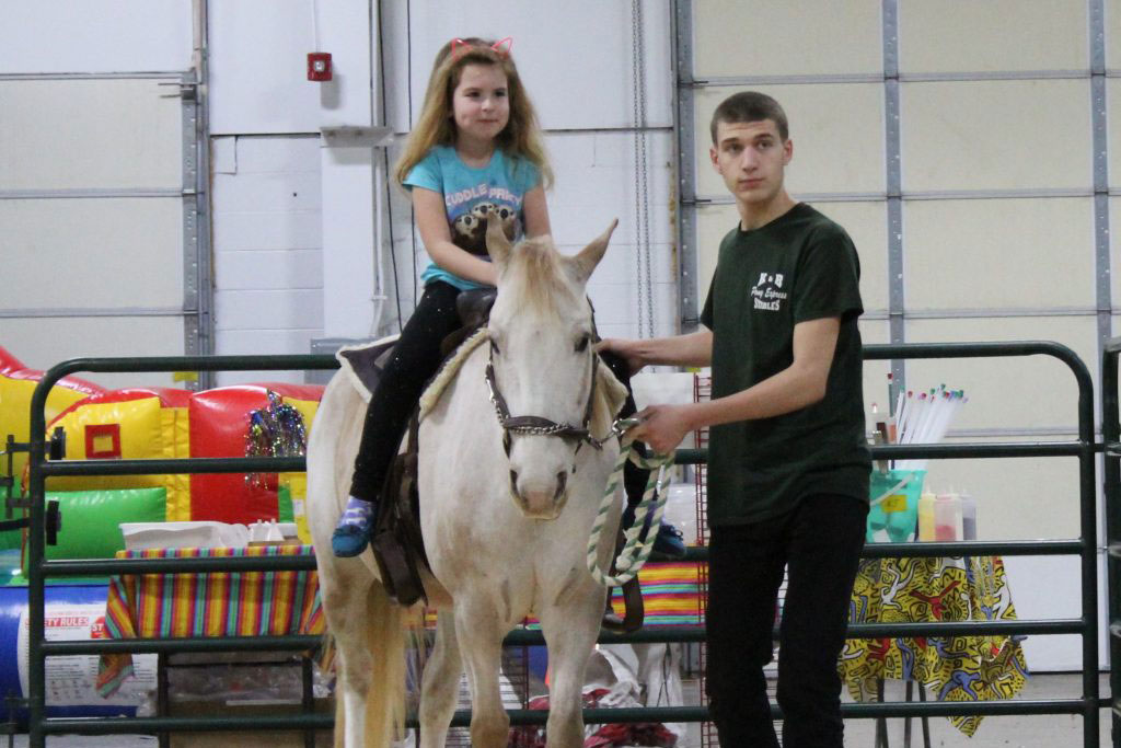 Little girl riding a horse at Pet expo