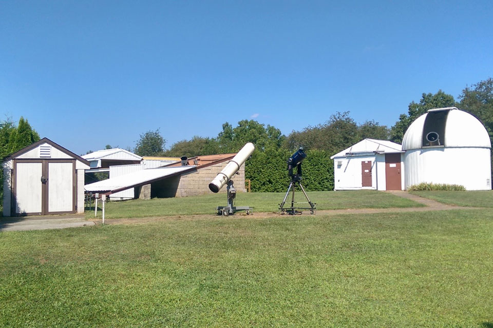 A group of white observatory buildings with a telescope on a lawn