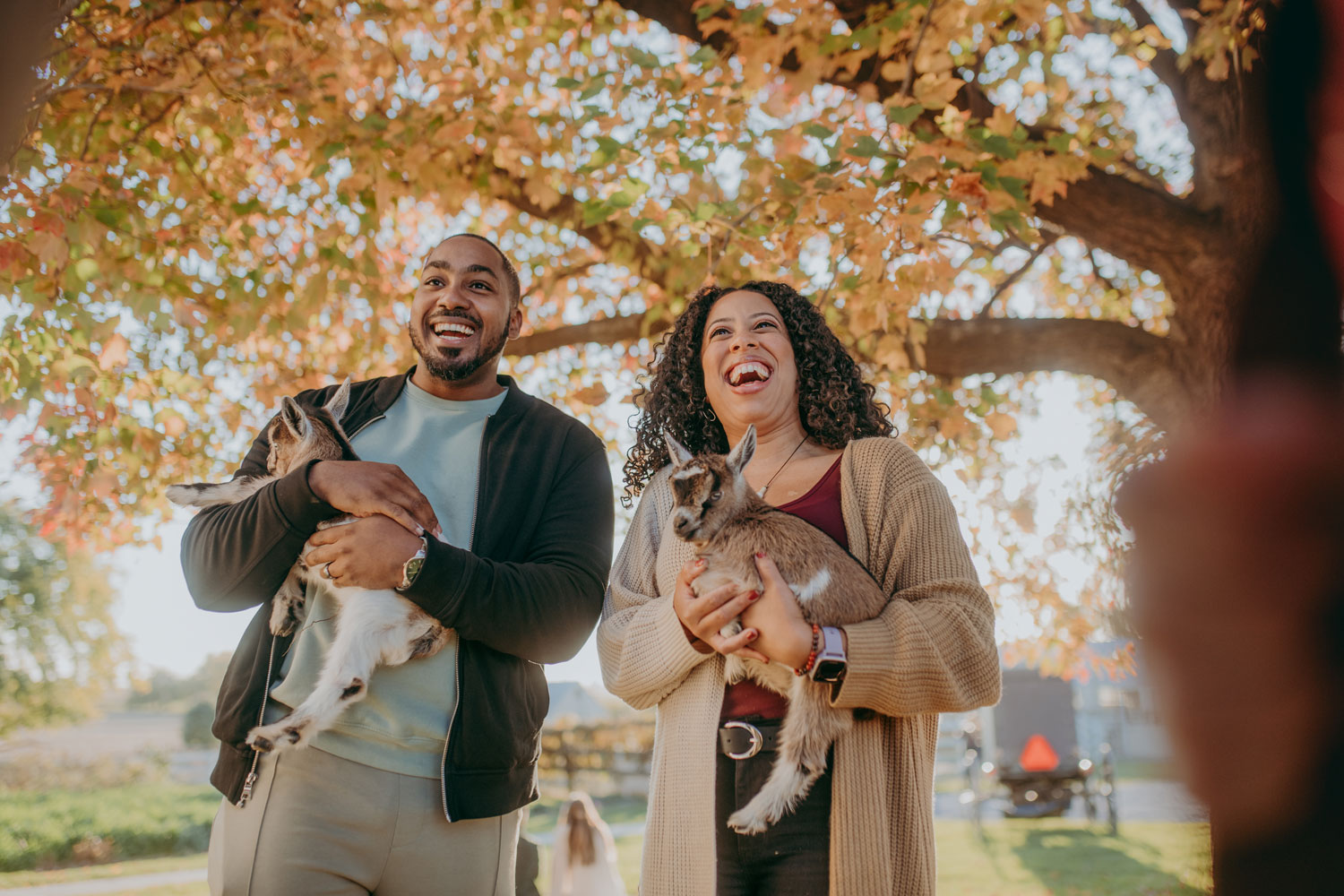 couple holding baby goats in arms at a Farm