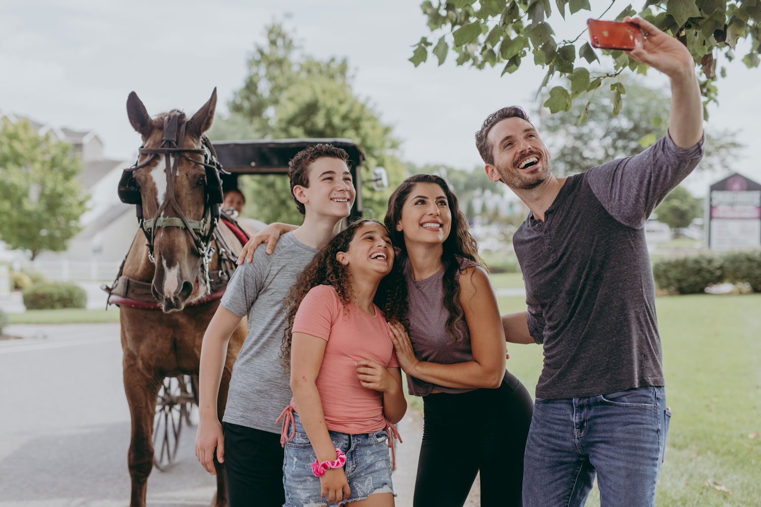 A family taking group selfie in front of a horse buggy