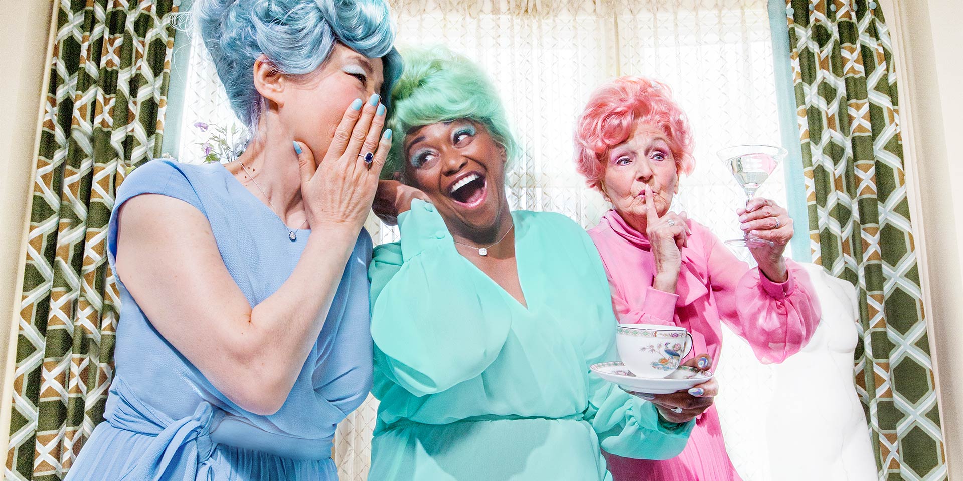 three ladies with colored hair and robes having drinks