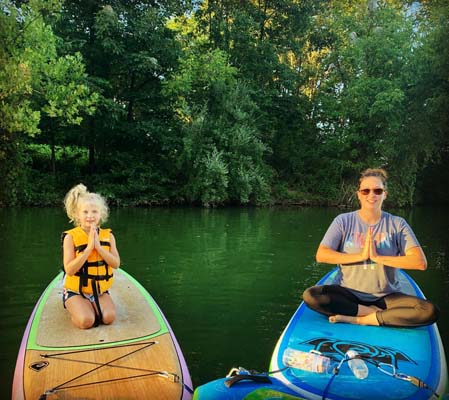 mother daughter doing Namaste sitting on a Paddle Boat