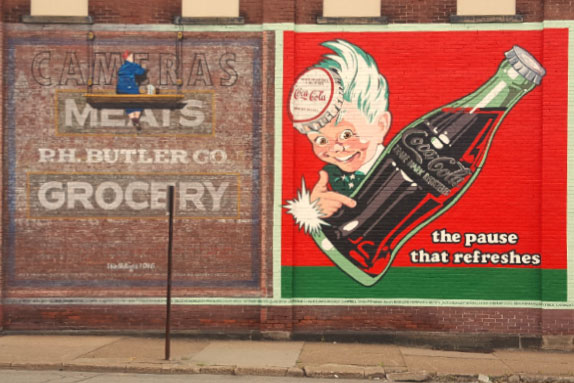 Kid holding cola mural on wall