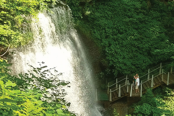 Couple taking pictures of Buttermilk falls standing on trail steps