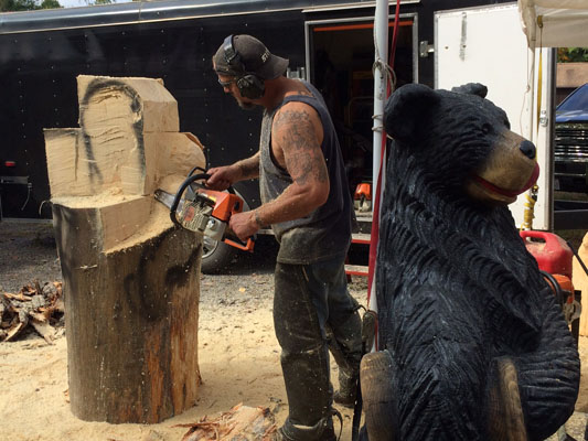 artist carving a wooden block with chainsaw