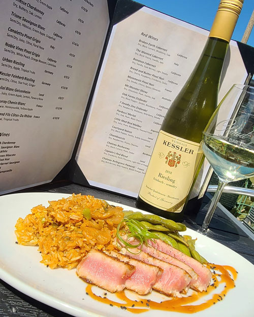 Medium rare serving on plate with wine bottle and menu