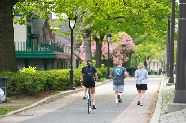 a couple jogging on right and a girl biking on left