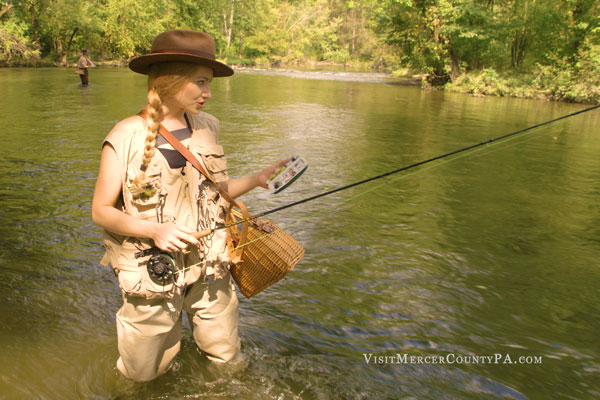 A lady fishing standing in Shenango River creek