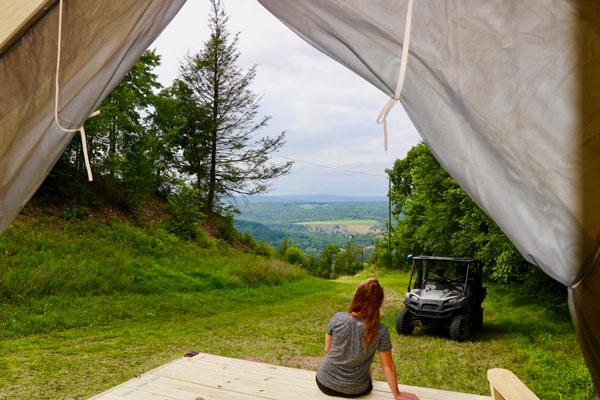 a women sitting infront of camping tent with beautiful view