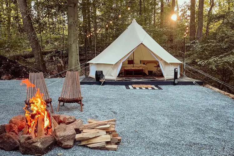 camp fire pit and two chairs on side infront of tent