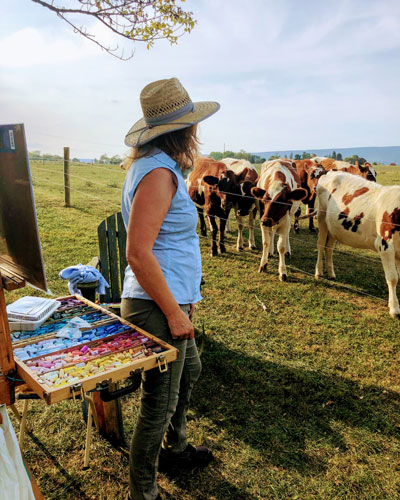 a women standing infront of a cow herd