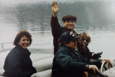 Danny Devito waving hand from boat along with Pam Prosser and two other 