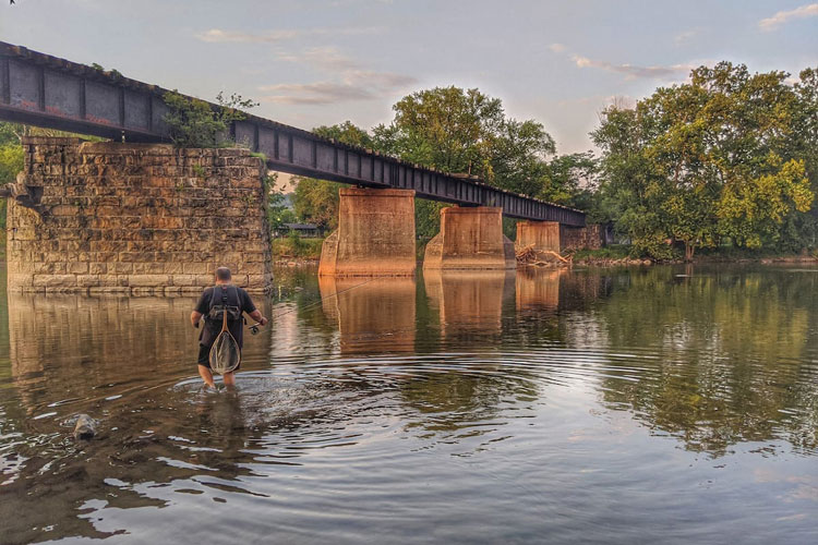 A person fishing on Juanita River next old bridge