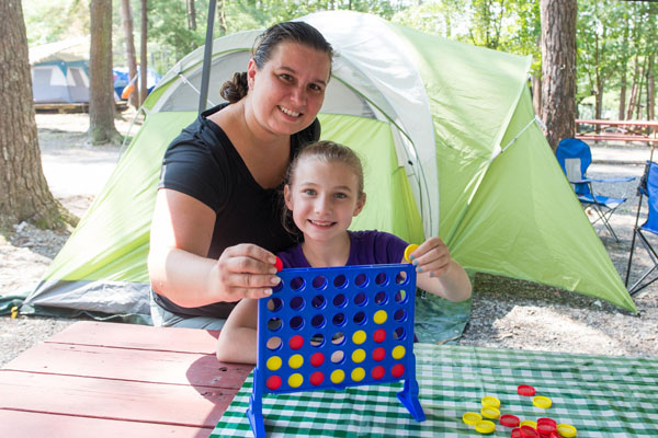 mother daughter playing four in a row game by camping tent