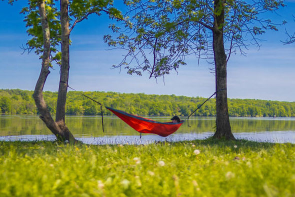 a person sleeping in hammock infront of lake