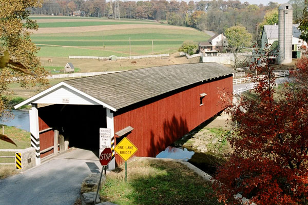 scenic view of farms behind covered bridge