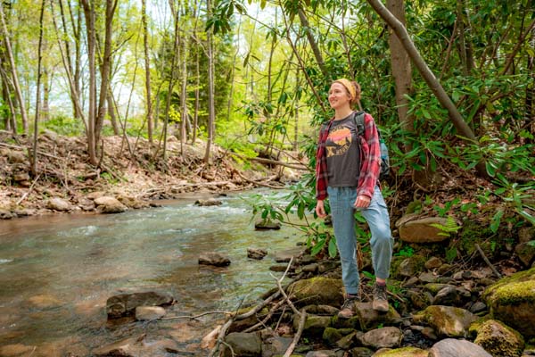 girl standing on boulders next to Creek