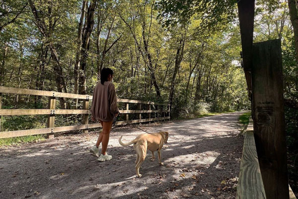 A lady walking her dog leashed on Trail