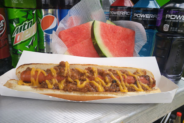 hotdog served on boat tray along side watermelon