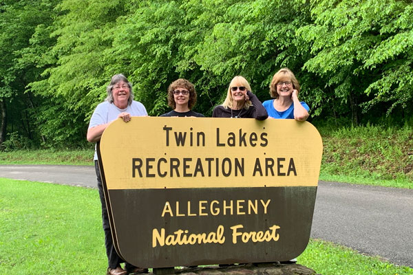 group of ladies behind a signage board posing for a photo