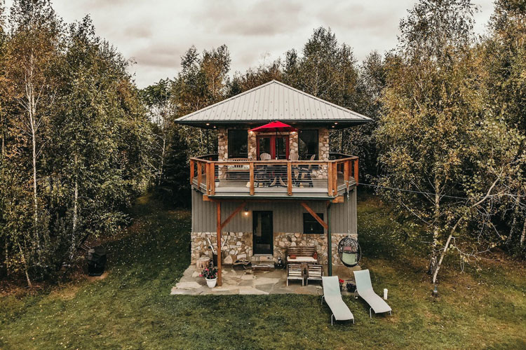 A house in the woods with a deck and chairs