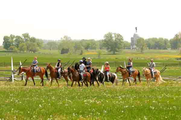group horse back riding thru farm fields