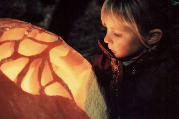 little girl looking at light coming from a carved pumpkin