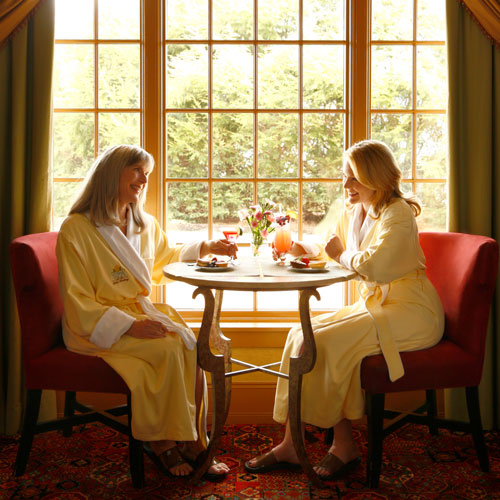 Two women sitting at a table having breakfast in robes
